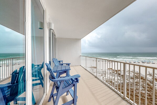 Enjoy the ocean view from this balcony with a table and chairs.