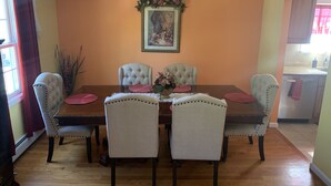 Ein Esszimmer mit Holztisch, vier gepolsterten Stühlen, einer floralen Tischdekoration und einem gerahmten Kunstwerk an der Wand.
