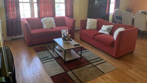 Ein Wohnzimmer mit zwei roten Sofas, einem Couchtisch und einer TV-Konsole.