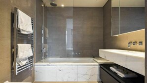 A modern bathroom with a bathtub, a large mirror, and a towel rack.
