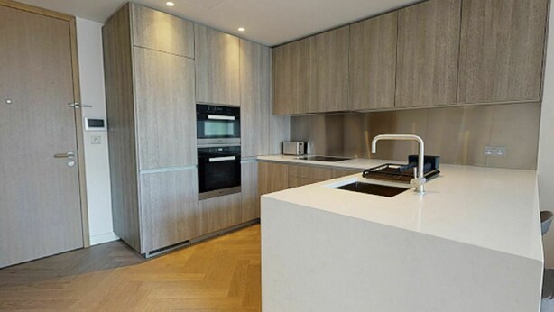A modern kitchen with wooden cabinets, a built-in oven, and a white countertop.