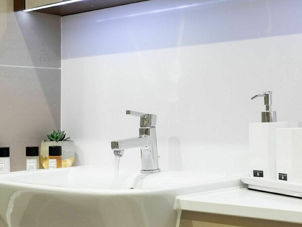 A modern bathroom with two sinks, a large mirror, and a potted plant.