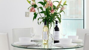 A dining table with a vase of flowers, two wine bottles, and white dinnerware. - Cosy apartment for 2 guests with WIFI and TV (London)