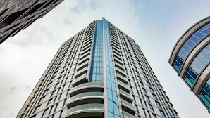 A tall, modern building with a curved glass facade and a central vertical feature. - Cosy apartment for 2 guests with WIFI and TV (London)