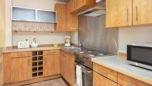 A modern kitchen with wooden cabinets, stainless steel appliances, and a microwave. - Lovely apartment for 2 people with WIFI and TV (London)