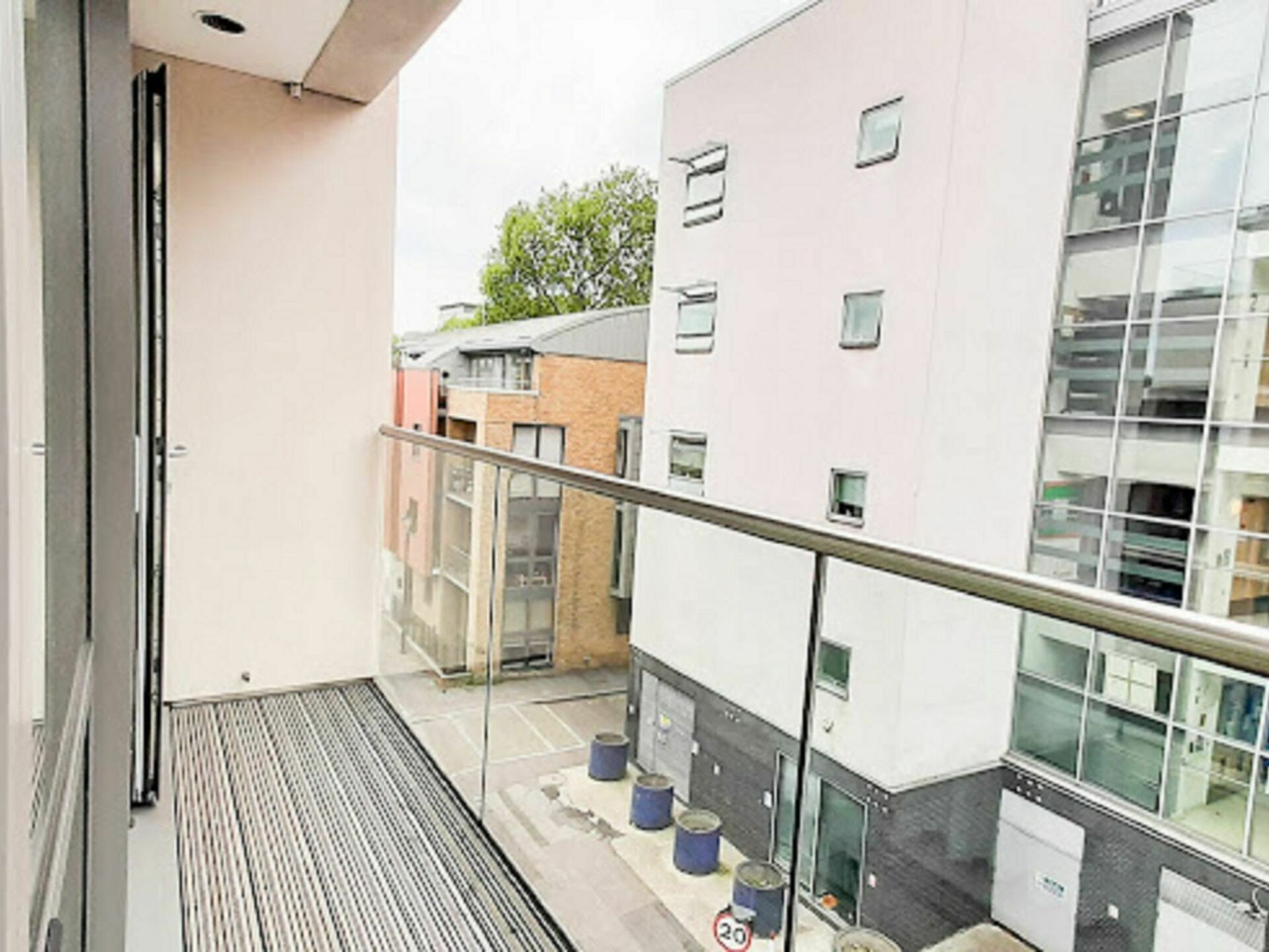 Ein Balkon mit Metallgeländer, der auf ein Gebäude mit vielen Fenstern und einer Ziegelaußenwand blickt.