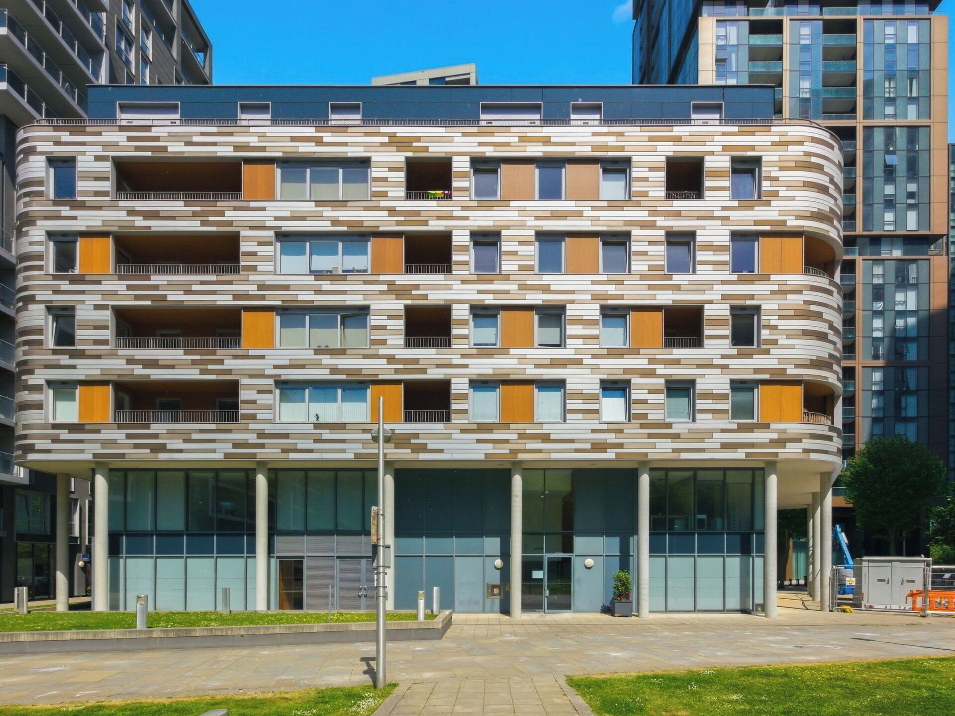En flervåningsbostadsbyggnad med en modern arkitektonisk design, utrustad med balkonger och stora fönster.