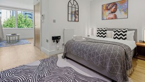 A modern bedroom with a bed, a radiator, a window, and a painting on the wall. - Lovely apartment for 2 guests with WIFI, TV and balcony (London)