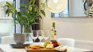 A dining table with a plant, wine glasses, a bottle of wine, and a cheese board with crackers and grapes. - Nice apartment for 4 guests with WIFI, TV and balcony (London)