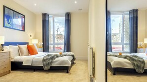A hotel room with two beds, a large window with curtains, a radiator, and a painting on the wall. - Nice apartment for 4 guests with WIFI, TV and balcony (London)