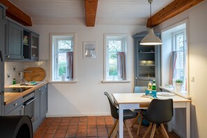 Une cuisine avec un plan de travail en bois, un évier et une fenêtre. On y trouve une table avec des chaises et un luminaire suspendu.