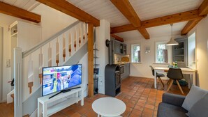 A spacious living area with a staircase, a television, a kitchen, and a dining area. - Vacation apartment Oldsum - Take a vacation in the artists' village of Oldsum (Oldsum)