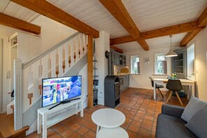 Uma sala de estar ampla com escada, televisão, cozinha e área de jantar.