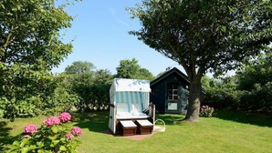 A small, cozy outdoor seating area with a striped canopy, a wooden bench, and a small table.