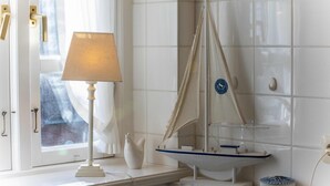 A room with a window, a lamp, and a model sailboat on a shelf.