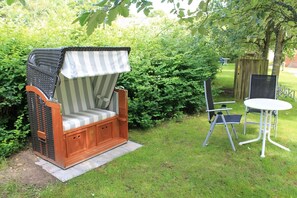 Un jardin avec un banc en bois, une table en métal et des chaises.
