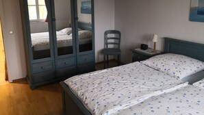 Une chambre à coucher comprenant un lit, une armoire, une chaise, une table de chevet et une horloge murale.
