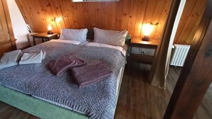 Een slaapkamer met houten lambrisering, een bed, twee nachtkastjes en een radiator.