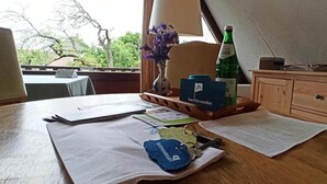 Een houten bureau met papieren, een fles en een vaas met bloemen.
