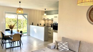 A modern living room with a grey sofa and a dining area with a table and chairs. - LocaJard House "Les Sternes" 400m from sandy beaches, 70m², 3 bedrooms (Saint-Vincent-sur-Jard)