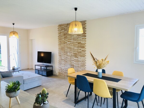 Un salon moderne doté d’un téléviseur à écran plat, d’un canapé, d’une table à manger avec des chaises et d’un mur décoratif en pierre.