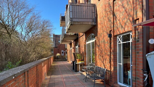 Ein Backsteinhaus mit einem Balkon, einem kleinen Tisch mit Stühlen und einem Blumentopf.