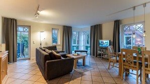 Ein geräumiges Wohnzimmer mit einer Couch, einem Esstisch und einem Fernseher.