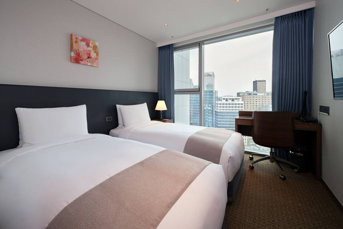 Ein Hotelzimmer mit zwei Betten, einem Schreibtisch und einem Stuhl.