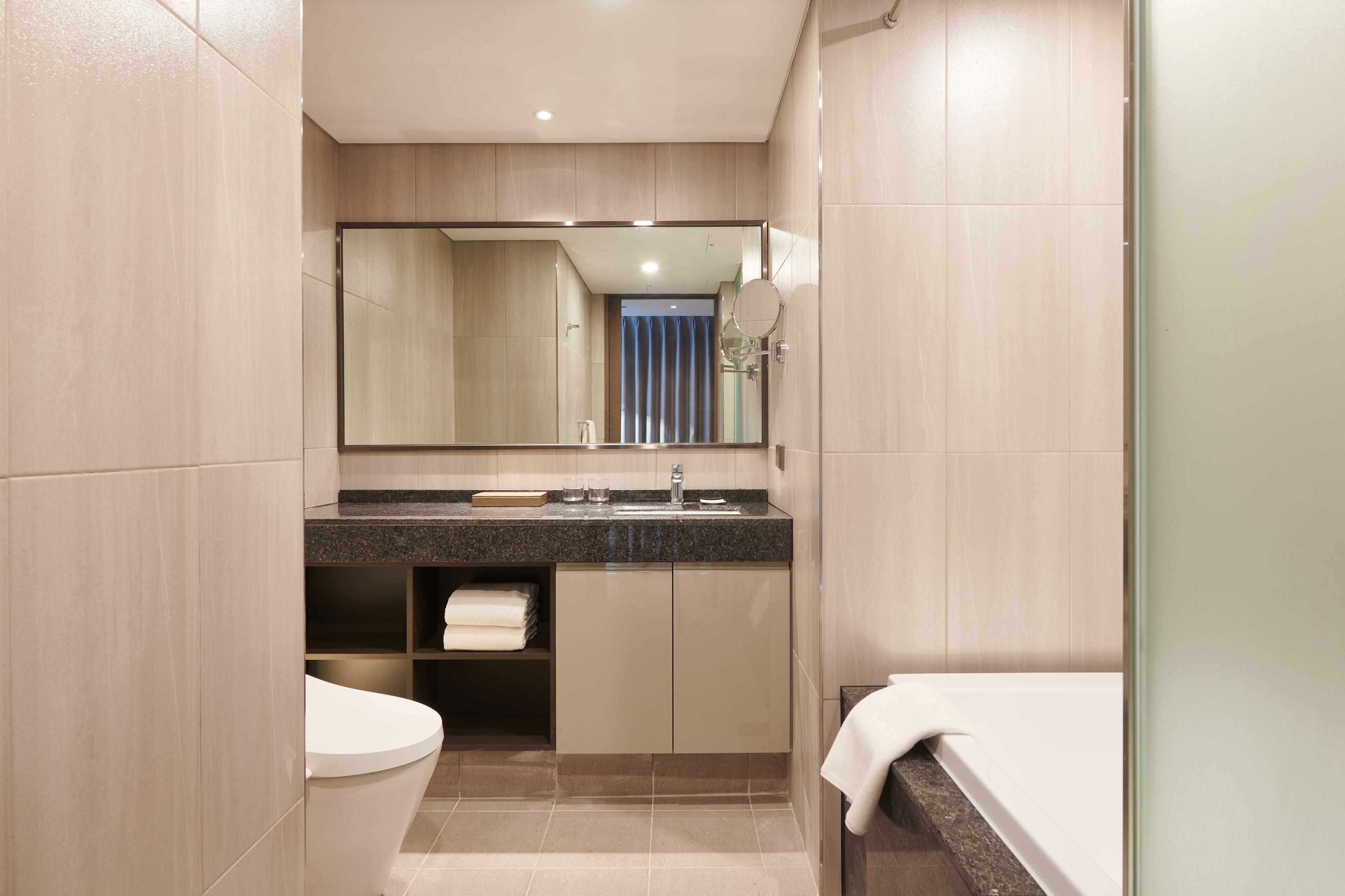 Een moderne badkamer met toilet, wastafel en spiegel.