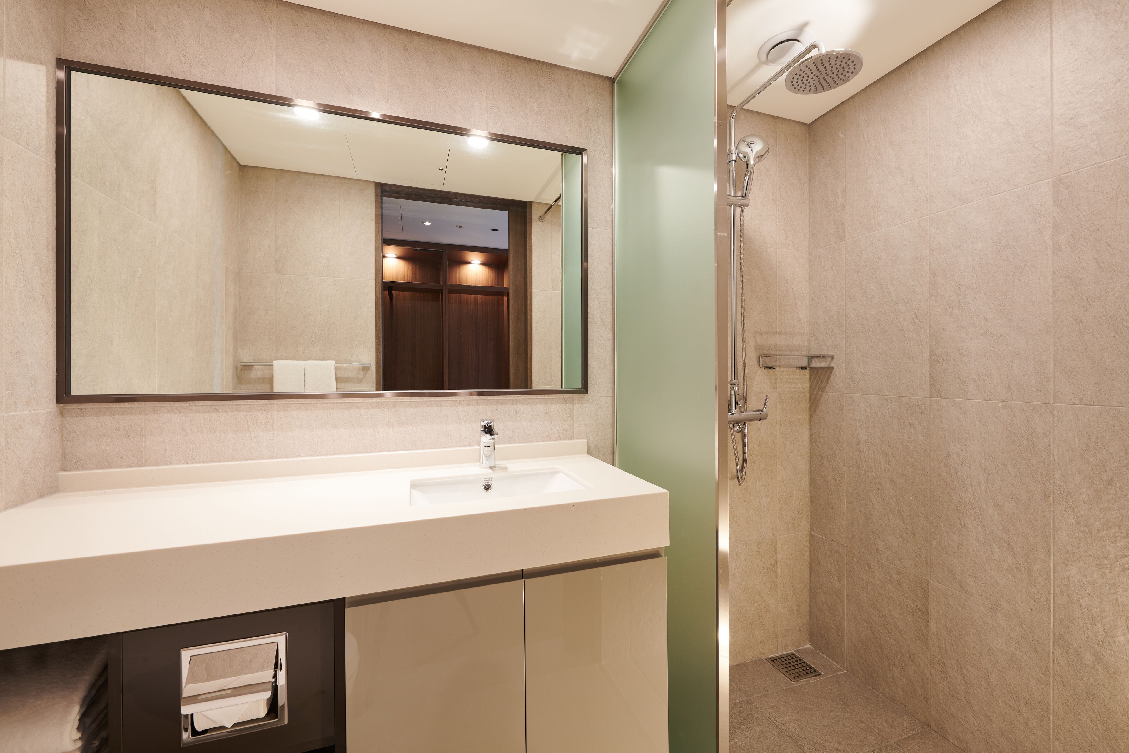 A modern bathroom with a large mirror, a sink, and a shower.
