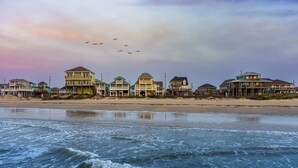 A beachfront property with multiple houses on stilts, a sandy beach, and waves crashing onto the shore. - New! Beachfront*Spectacular Views*4 bdrm House*Sleeps 14 (Crystal Beach)