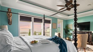 A bedroom with a four-poster bed, a ceiling fan, a TV, and a view of the outdoors. - New! Beachfront*Spectacular Views*4 bdrm House*Sleeps 14 (Crystal Beach)