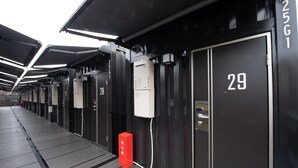 A row of hotel rooms with individual numbers on the doors, a red fire alarm box, and a covered walkway. - HOTEL R9 The Yard Oyamayokokura (Oyama)