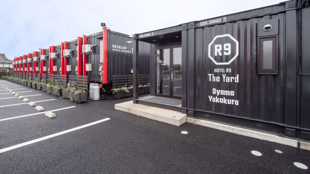 A row of black hotel containers with red accents, labeled "R9 Hotel R9 The Yard Oyama Yokokura." - HOTEL R9 The Yard Oyamayokokura (Oyama)
