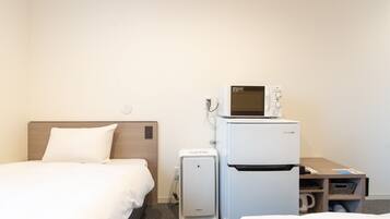 A hotel room with a bed, a small refrigerator, a microwave, and a coffee maker.