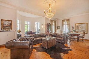 Amplia sala de estar con un sofá seccional de cuero grande, una mesa de centro de madera y un candelabro.