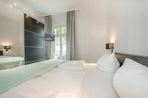 Ein modernes Hotelzimmer mit einem großen Bett, einer dunklen Akzentwand und Blick ins Freie.