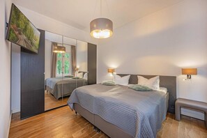 Ein Schlafzimmer mit einem großen Bett, zwei Nachttischen, einem Spiegel und einer Deckenleuchte.