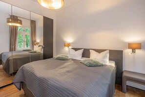 Una habitación de hotel con dos camas, un espejo grande y lámparas fijadas a la pared.