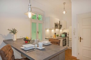Una cocina moderna con una isla central, armarios blancos y una zona de comedor con una silla marrón.