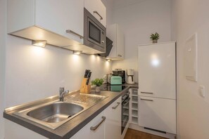 A modern kitchen with a stainless steel sink, a microwave, a toaster, and a refrigerator. - Beautiful vacation apartment in Heringsdorf with garden, only 150 m to the sea - Villa (Heringsdorf)