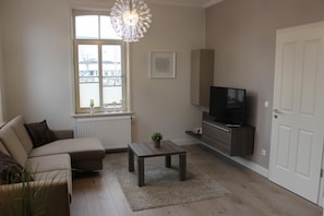 A living room with a sofa, a coffee table, a TV, and a radiator.