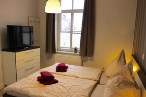 Une chambre d’hôtel avec deux lits, une télévision, une fenêtre avec des rideaux et un radiateur.