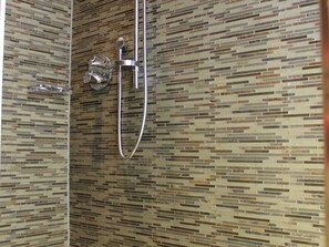 A shower with a modern design, a handheld showerhead, and a wall with a mosaic tile pattern. - Altstadt Borkum Apartment 1 Lütje Hörn - Altstadt Villa Borkum (Borkum)