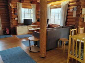 A log cabin interior with a sofa, dining table, chairs, a television, and a fireplace. - Heinäsorsa by Interhome (Joutsa)
