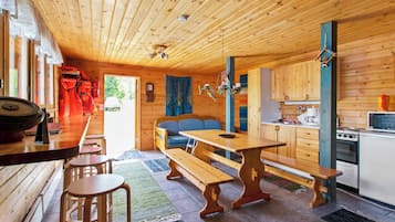 A wooden cabin interior with a dining area, kitchen, and seating space.