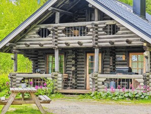 A log cabin with a porch, a picnic table, and a grill outside. - Heinäsorsa by Interhome (Joutsa)
