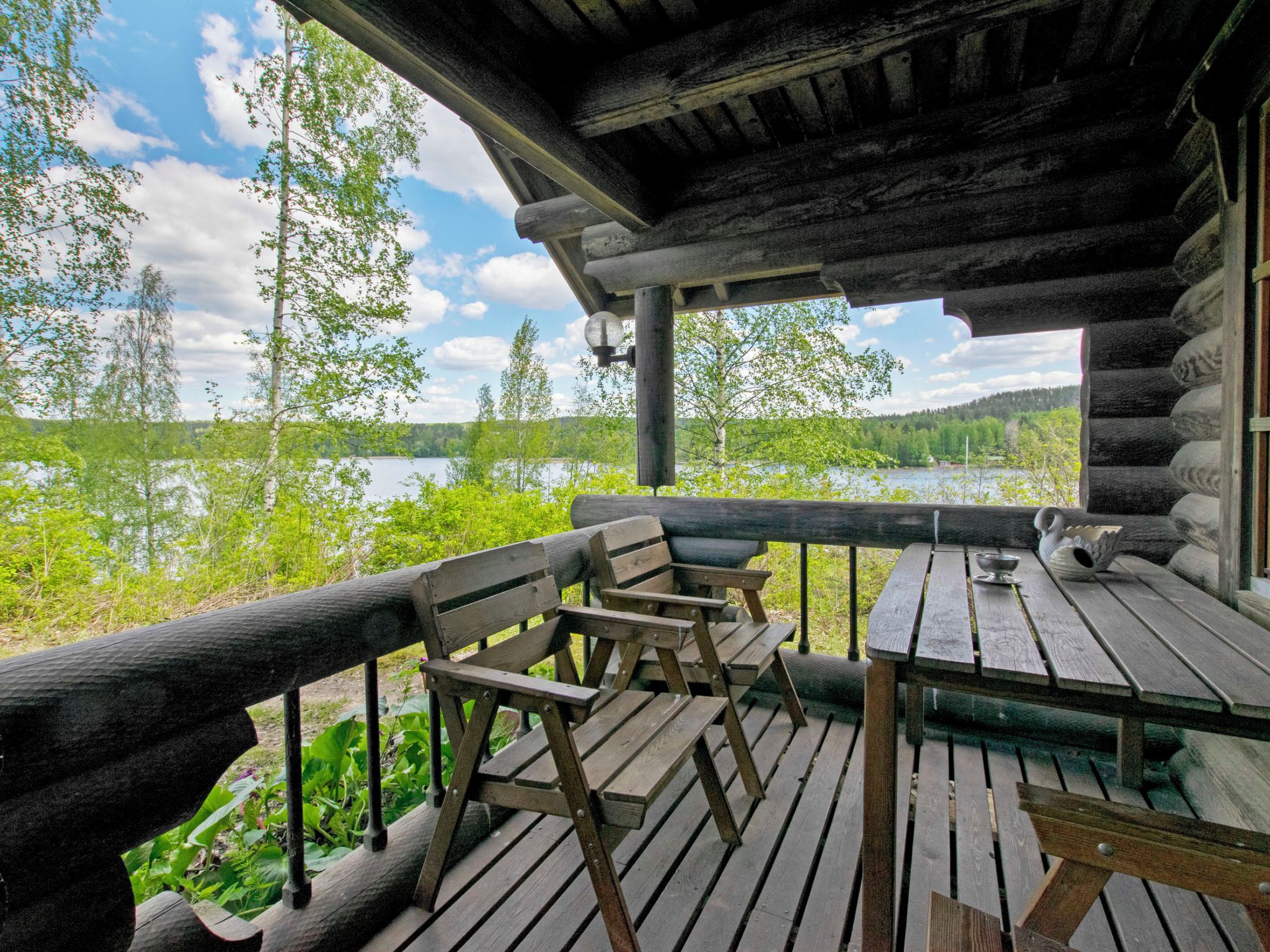 A wooden deck with a table and chairs overlooking a lake.