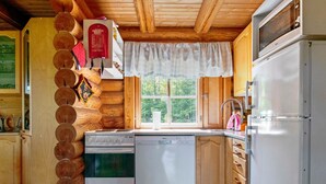 A compact kitchen with wooden cabinets, a stove, a dishwasher, and a refrigerator. - Heinäsorsa by Interhome (Joutsa)