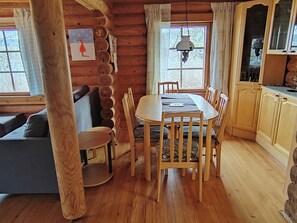 A wooden interior with a dining table, chairs, a sofa, and a kitchen area. - Heinäsorsa by Interhome (Joutsa)